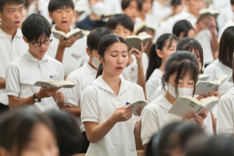 聖書を手に讃美歌を歌う生徒たち